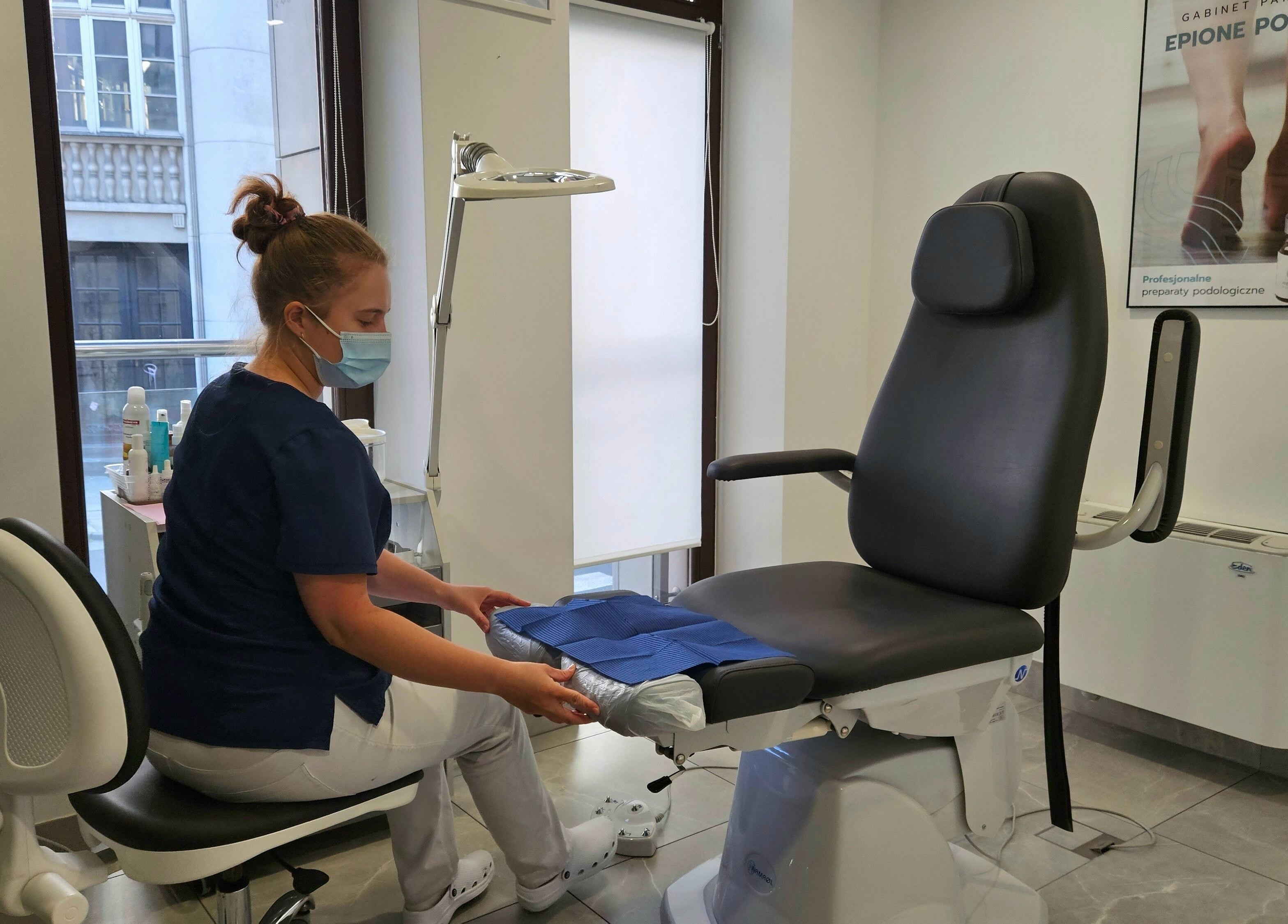 Specjalistka w Propodis Małopolskie Centrum Zdrowej Stopy, Kraków, PL, przygotowuje fotel do zabiegu podologicznego.