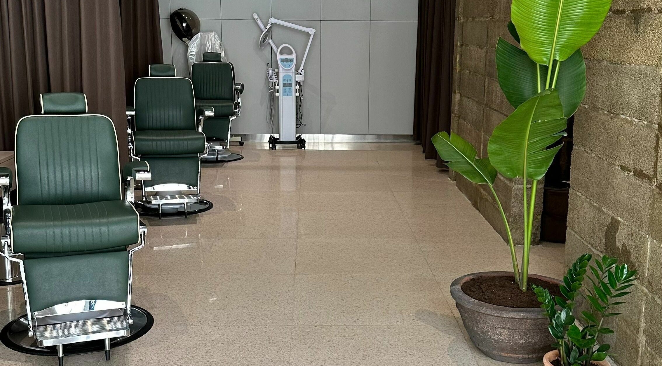 Elegant barber chairs at Float Barbershop, Sharjah, Sharjah, AE, surrounded by green plants for a relaxing vibe.