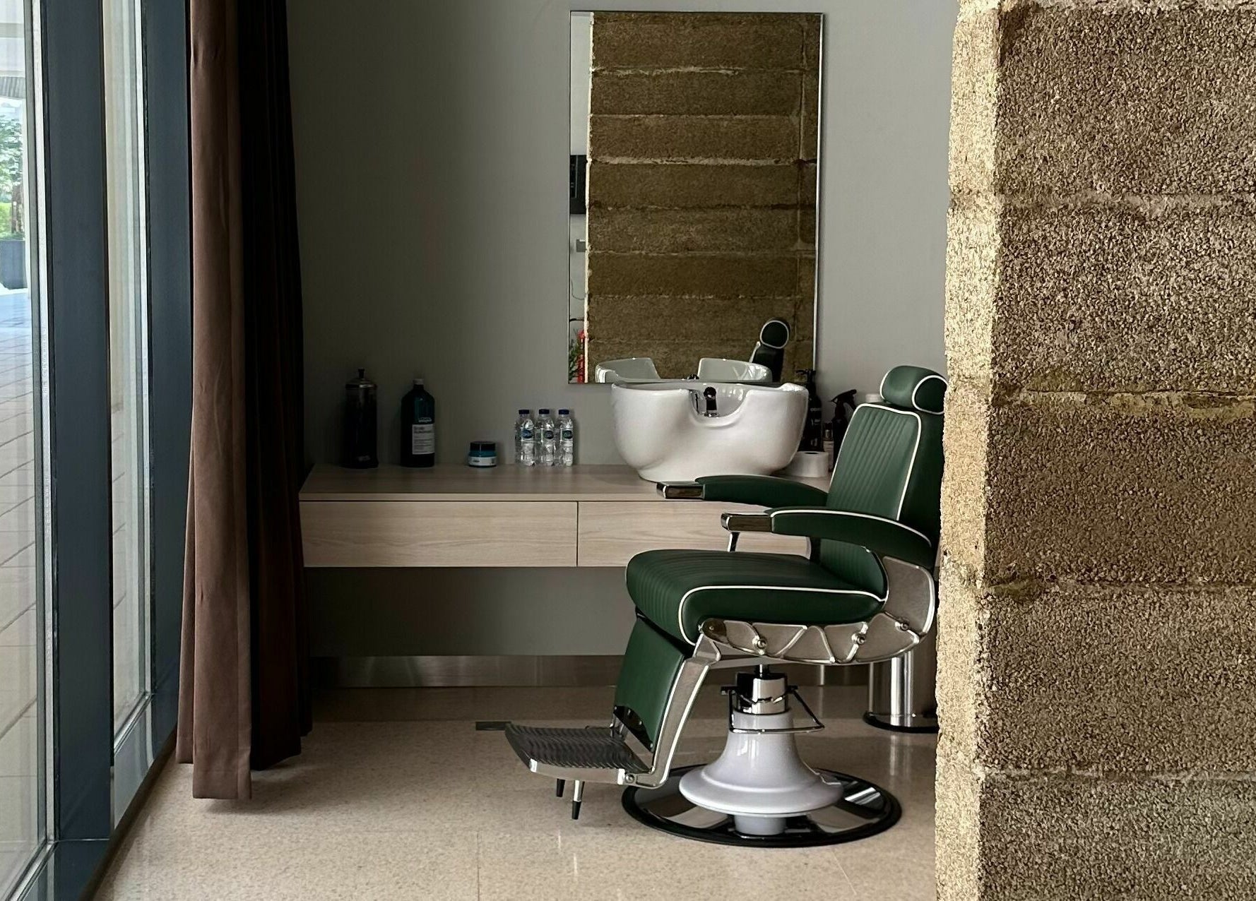 Sleek barber station at Float Barbershop, Sharjah, Sharjah, AE featuring green leather chair and modern decor.