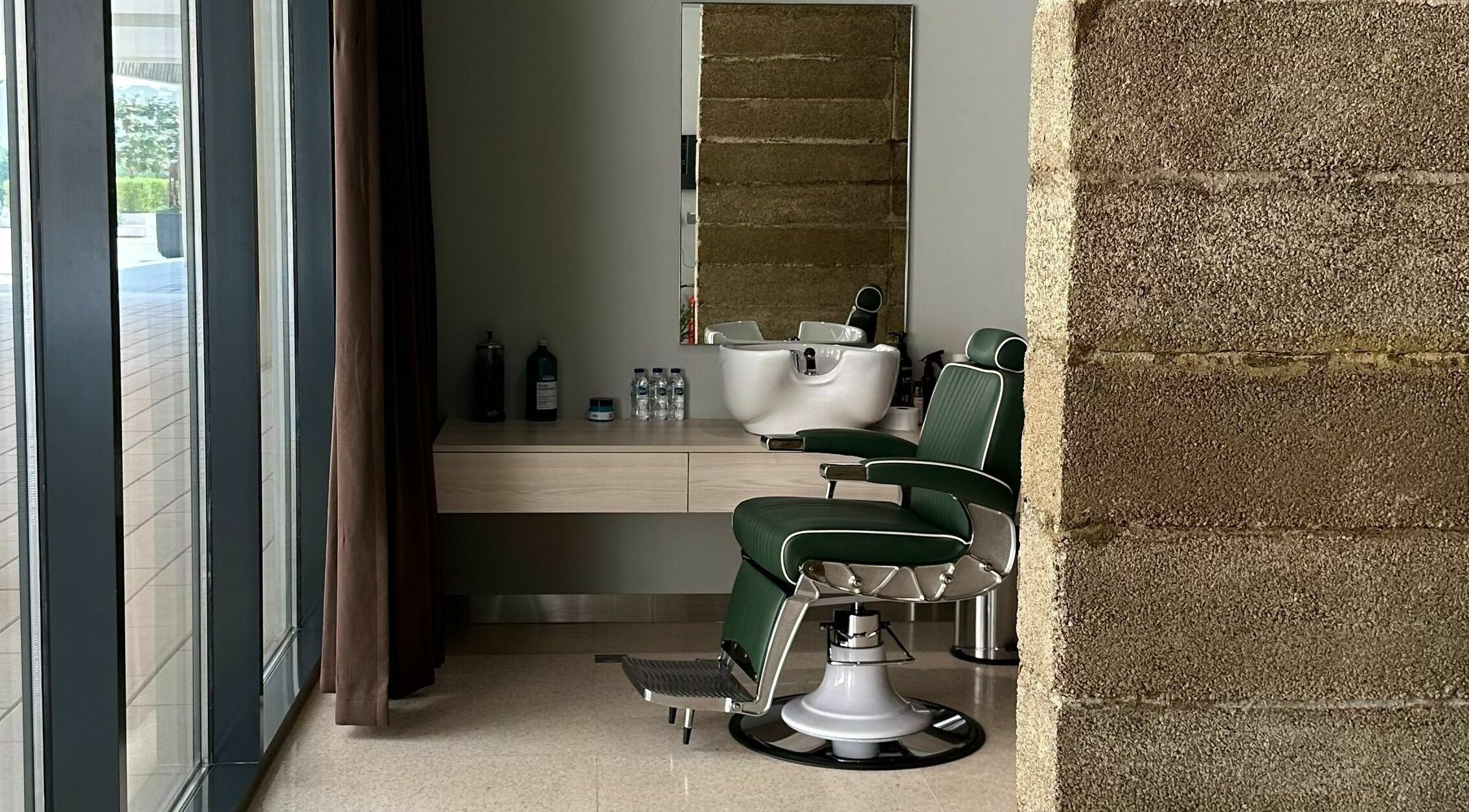 Sleek barber station at Float Barbershop, Sharjah, Sharjah, AE featuring green leather chair and modern decor.