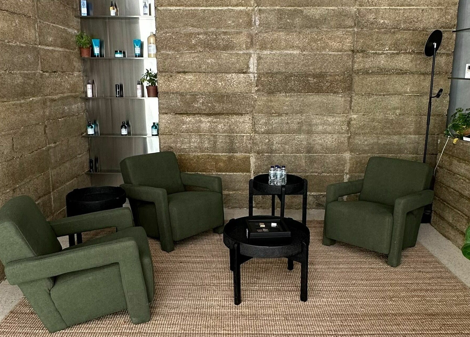 Cozy seating area at Float Barbershop, Sharjah, Sharjah, AE with green chairs and stone walls.