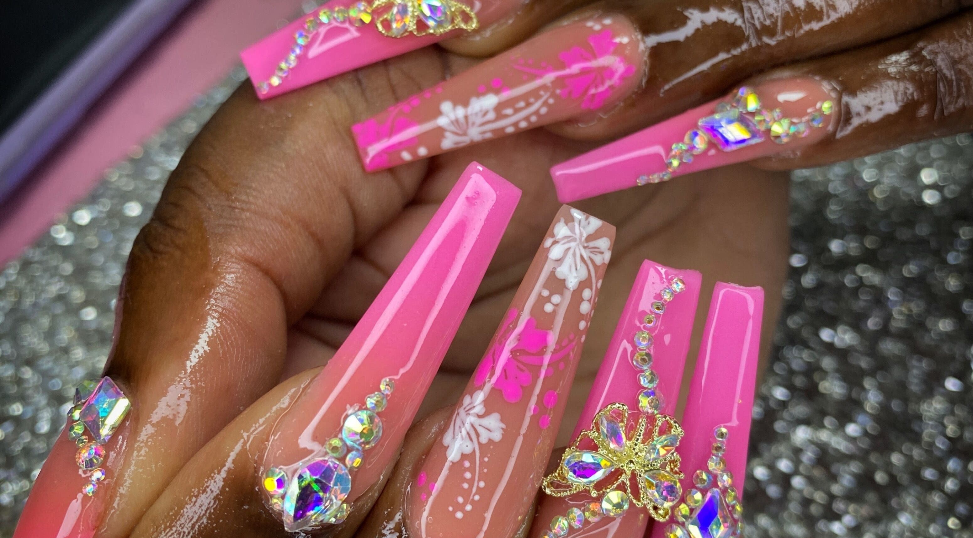 Beautiful pink acrylic nails with intricate designs at K’ Oari Nail Artistry, Potters Village, Saint John, AG.