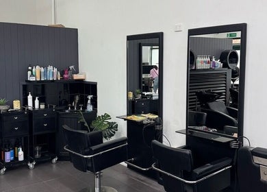 Modern hairstyling area at Oxenford Hair & Beauty, Oxenford, Queensland, AU with black salon chairs and mirrors.