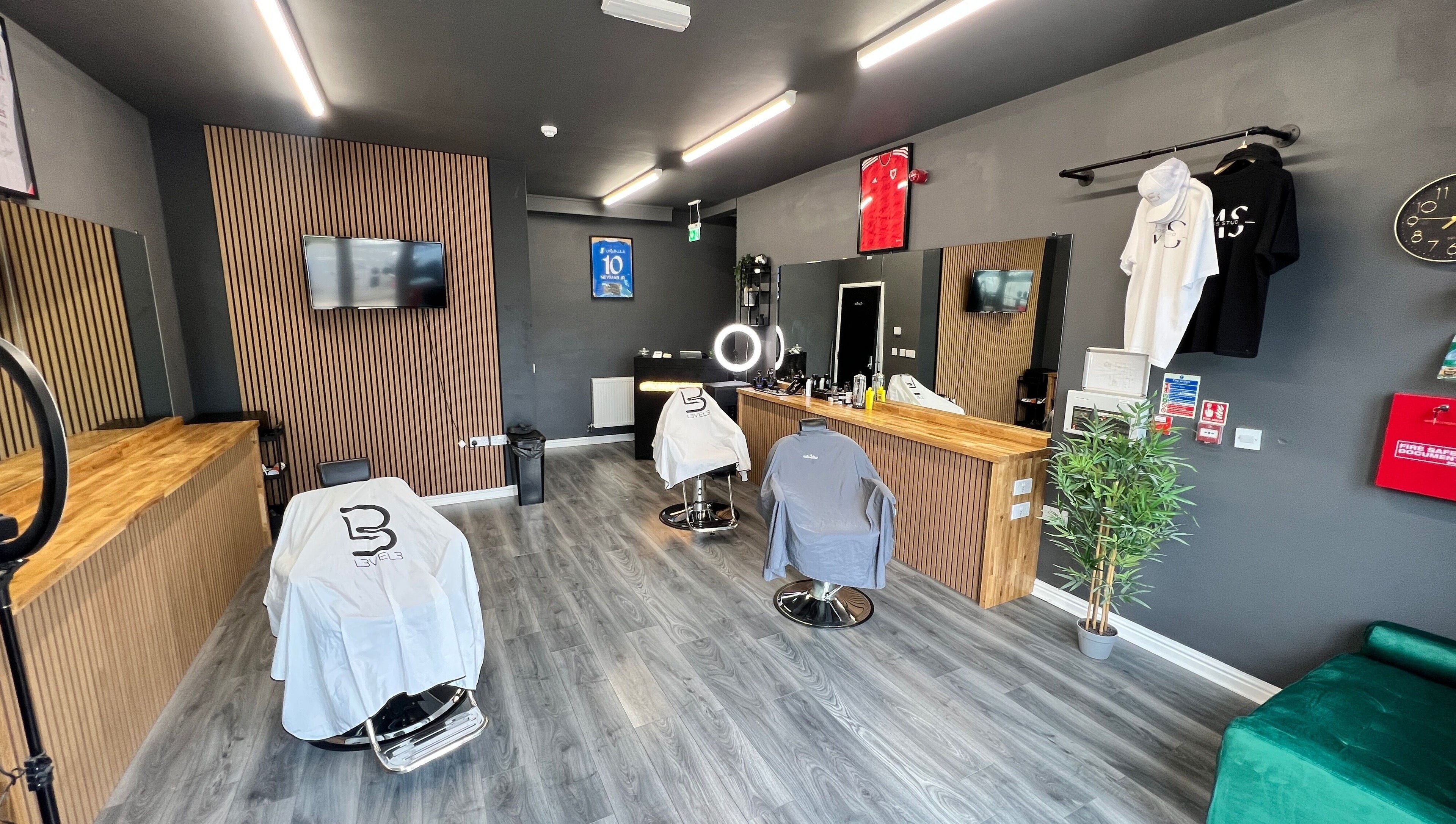 Modern Moss Barber Studio interior in Llantrisant, Wales, GB with sleek styling stations and mirror lighting.
