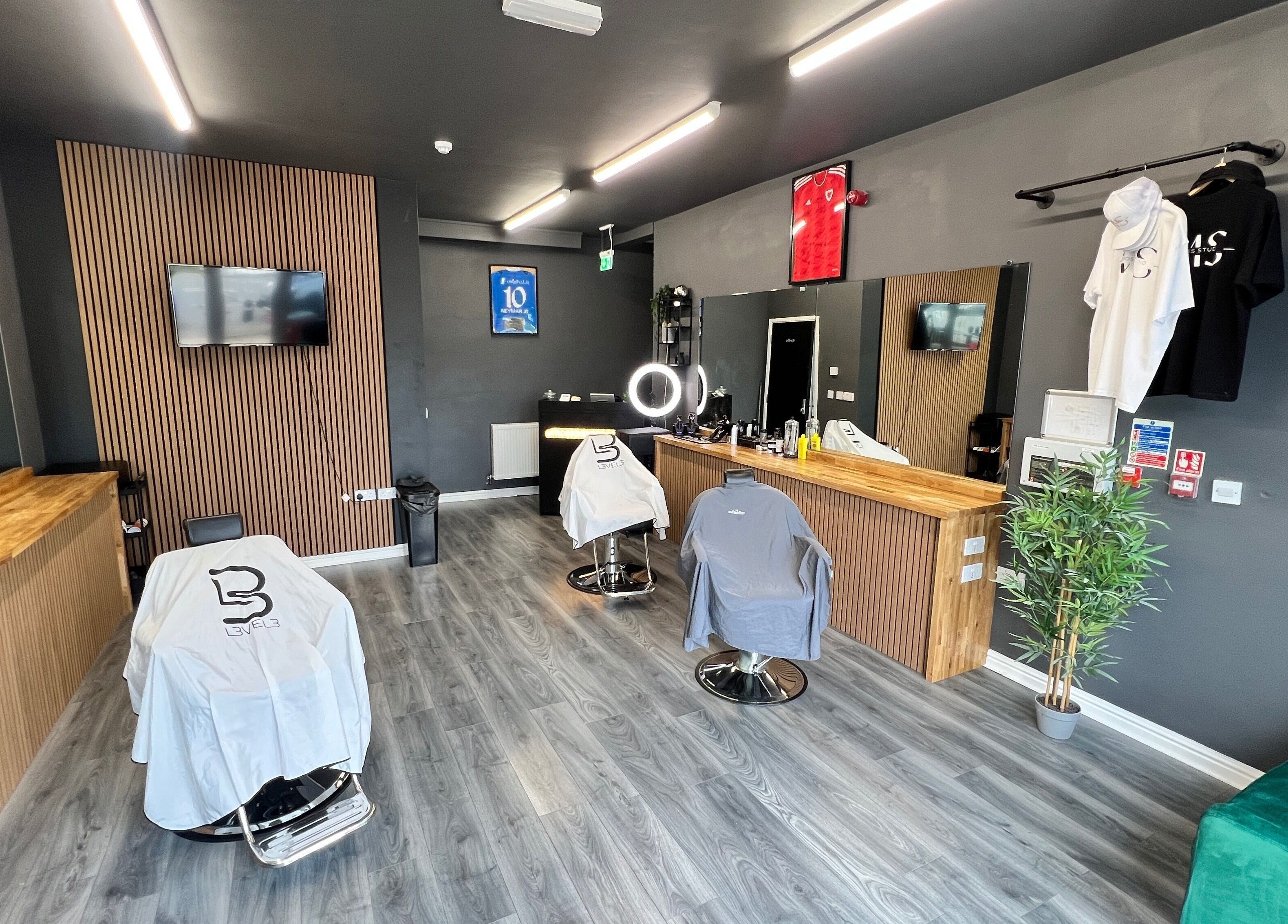 Modern Moss Barber Studio interior in Llantrisant, Wales, GB with sleek styling stations and mirror lighting.