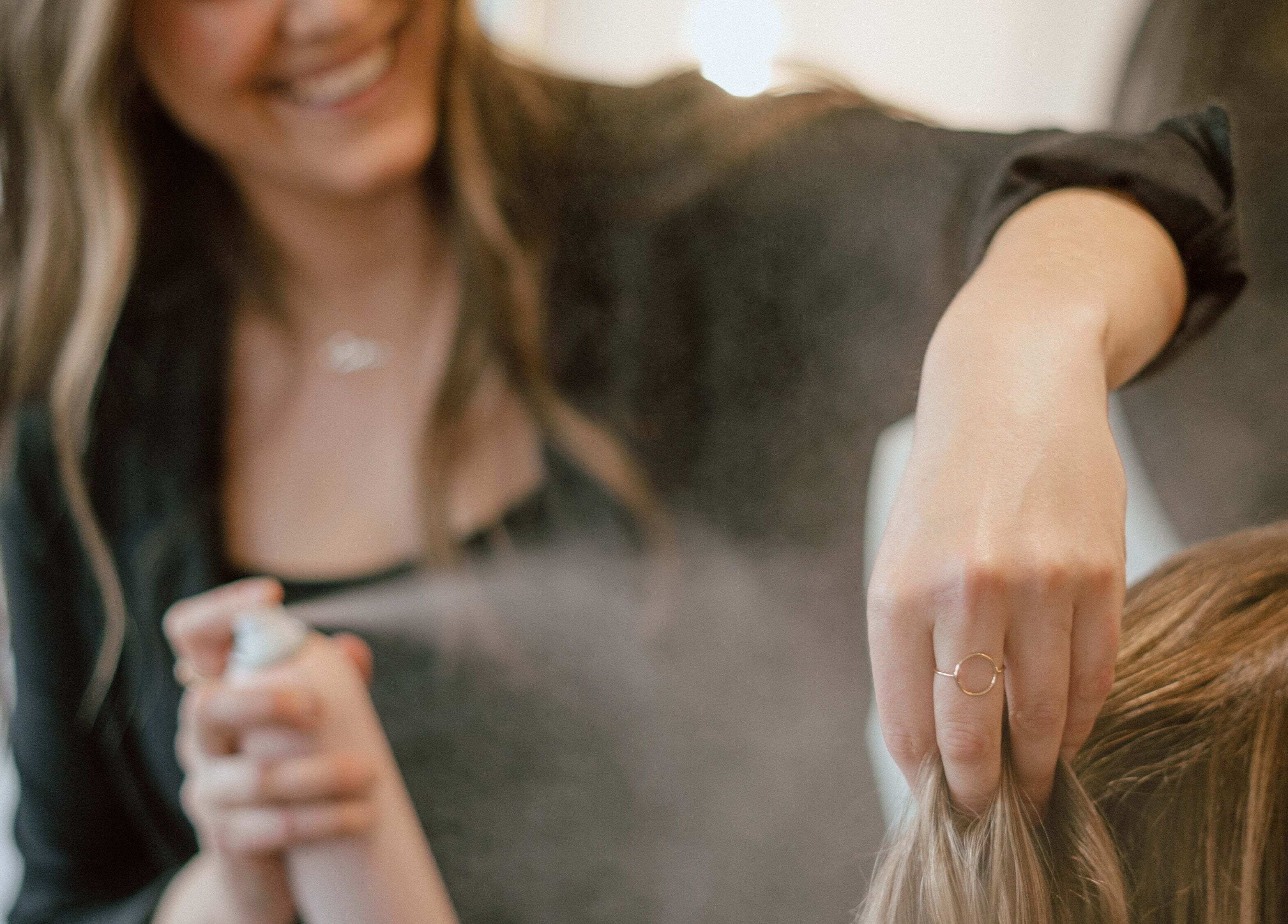 Hairstylist applying hair spray at Glow Hair Studio in Thorold, Ontario, CA.