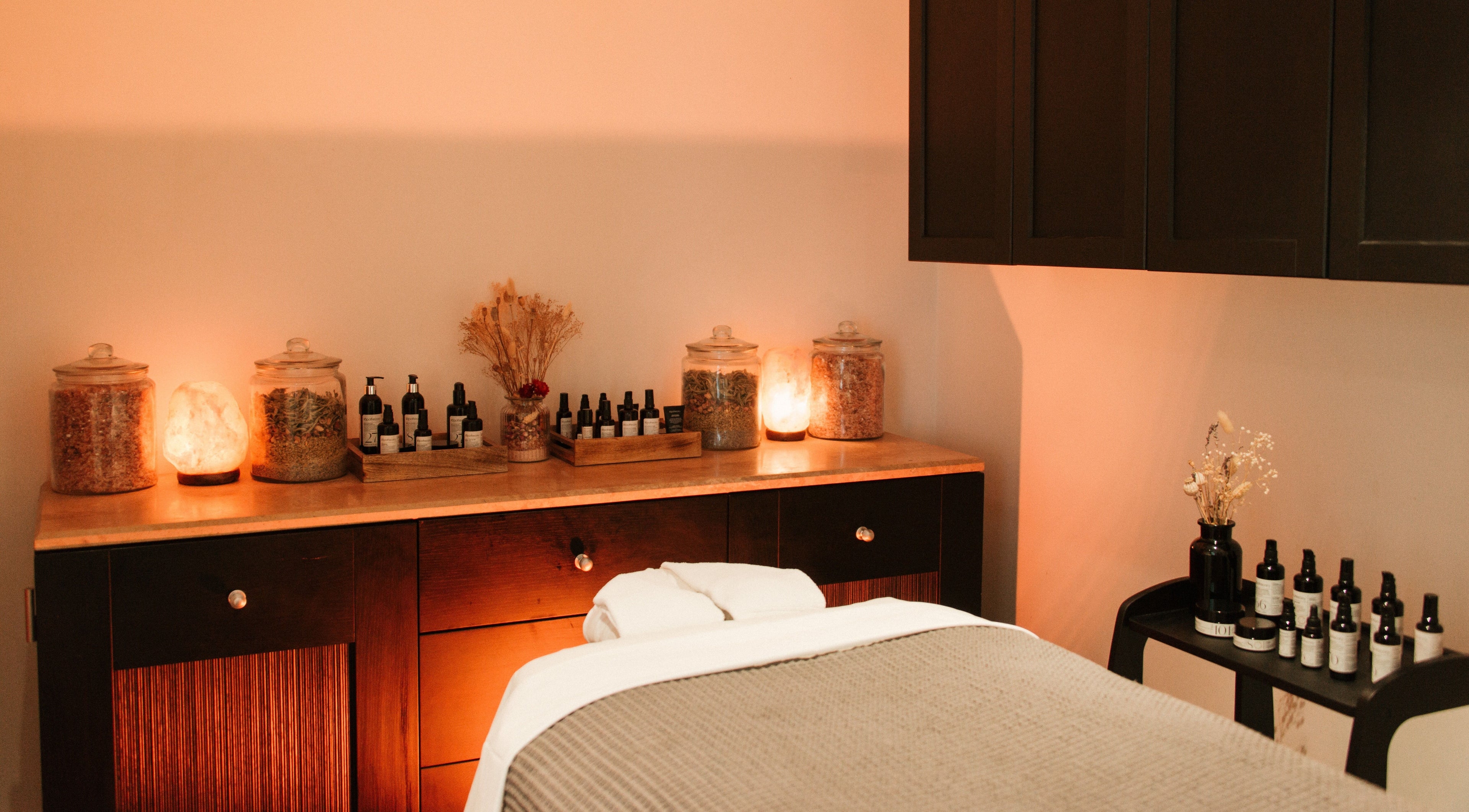 Warm and tranquil ilapothecary treatment room in London, England, GB, with massage table and ambient lighting.