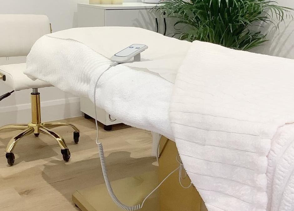 Massage table in a serene room at Blossom Leaf, Bognor Regis, England, GB, with a lush plant in the background.