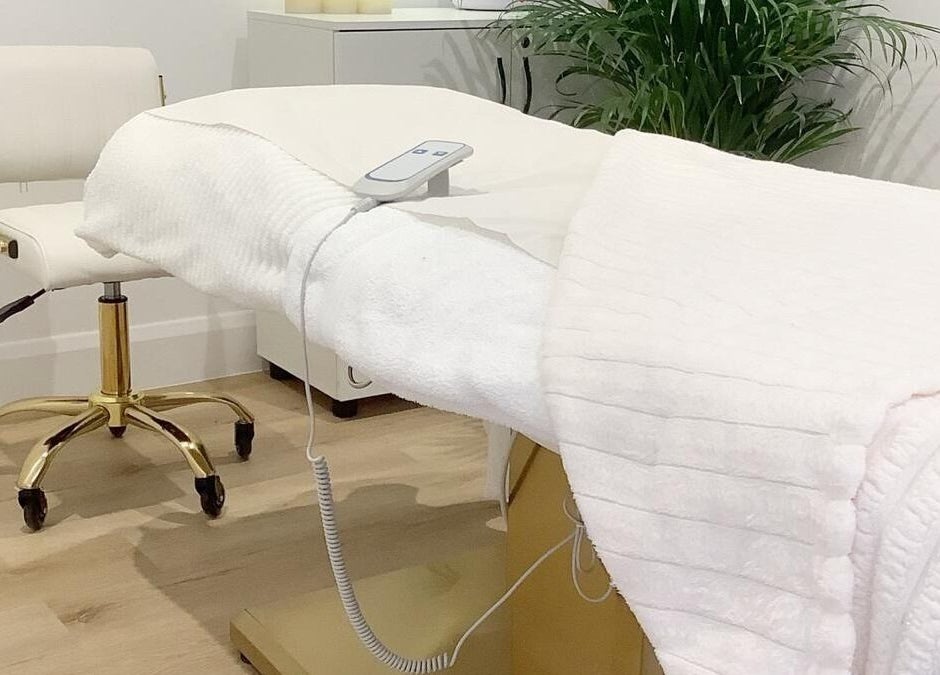 Massage table in a serene room at Blossom Leaf, Bognor Regis, England, GB, with a lush plant in the background.