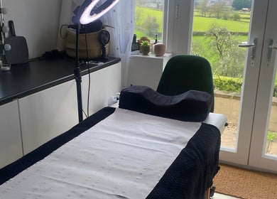 Calm treatment room at Flos’ Beauty Box in Stroud, England, GB with scenic garden view.