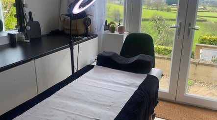 Calm treatment room at Flos’ Beauty Box in Stroud, England, GB with scenic garden view.
