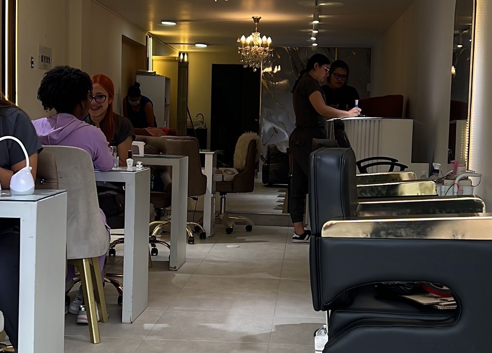 Interior de Angie Arevalo Nails Spa en Bogotá, con clientas en estaciones de manicura.