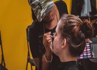 Makeup artist at Visage the Look in Saint Michael, BB, applying eyeshadow to a client in a vibrant, warm setting.