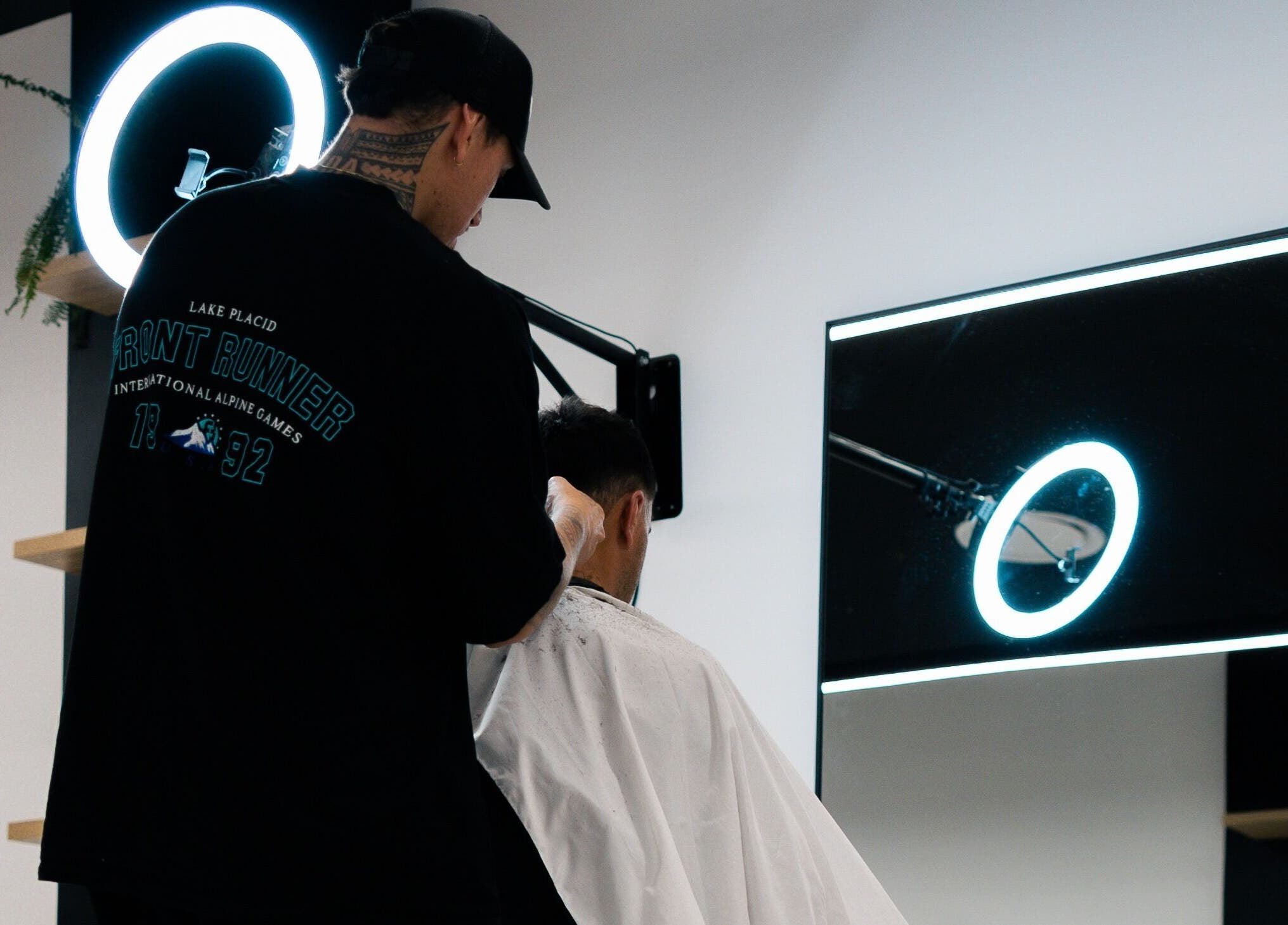 Barber crafting a stylish haircut at Eleven 11 Barber Studios, Coomera, Queensland, AU under a halo light.