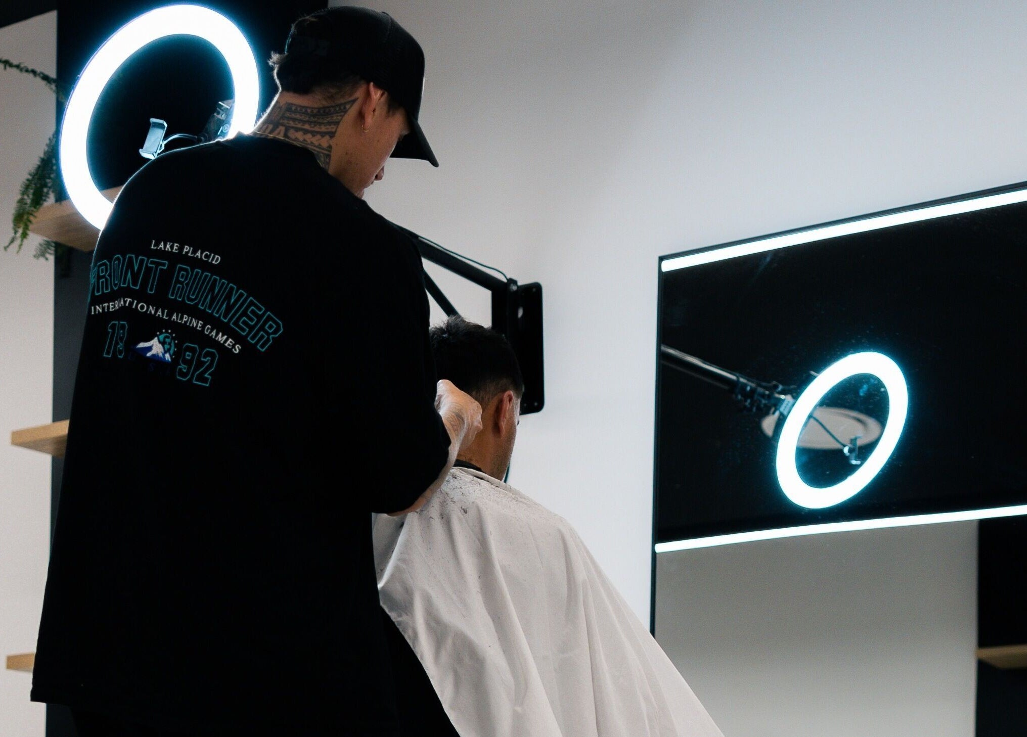 Barber crafting a stylish haircut at Eleven 11 Barber Studios, Coomera, Queensland, AU under a halo light.