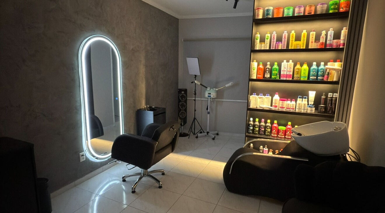 Interior moderno do salão Dani Manja Cabelos em São Paulo, com espelho iluminado e prateleira de produtos.