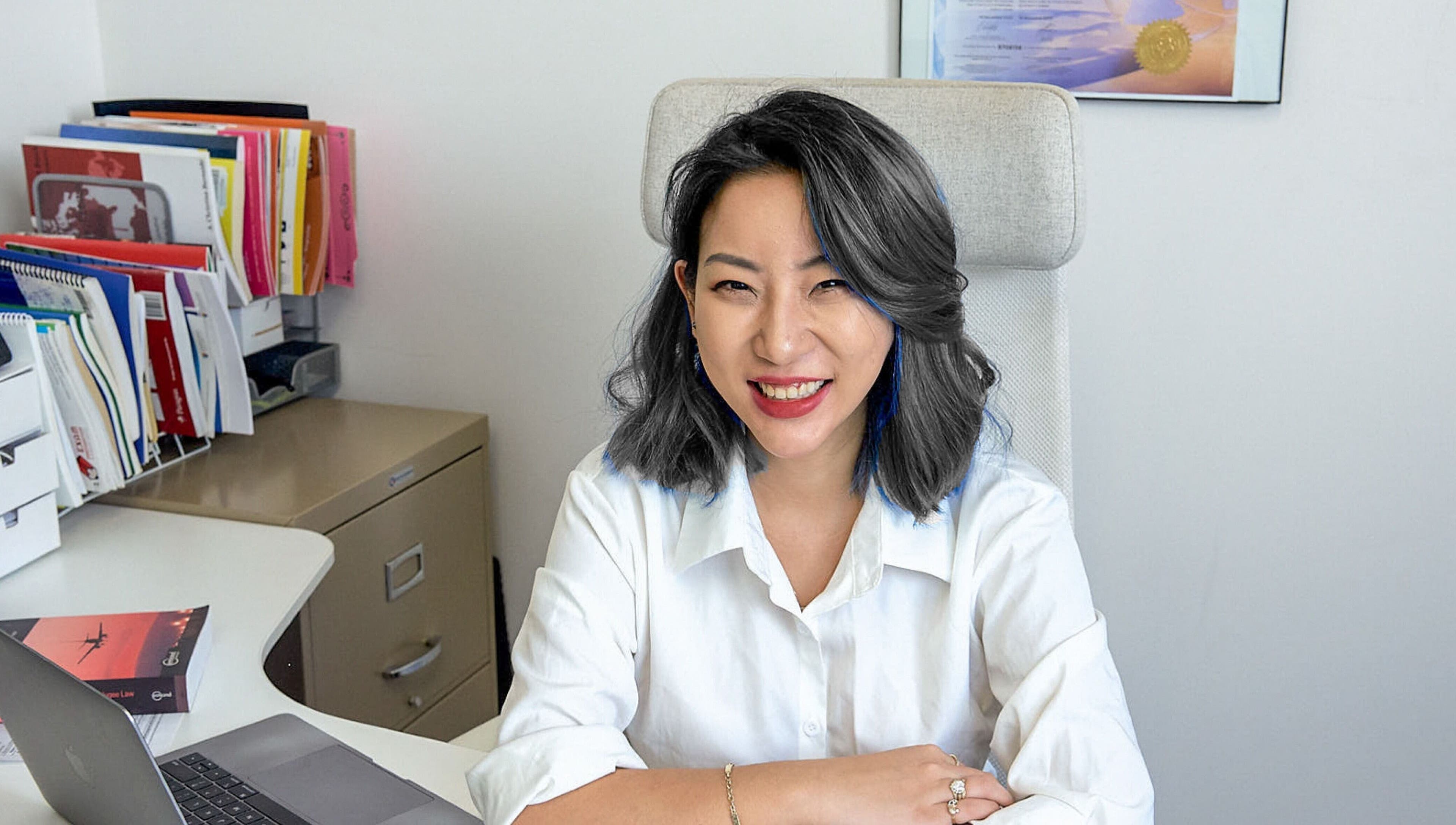 Professional consultant smiling at desk in Nohproblem Immigration and Education Consulting, Vancouver, BC.