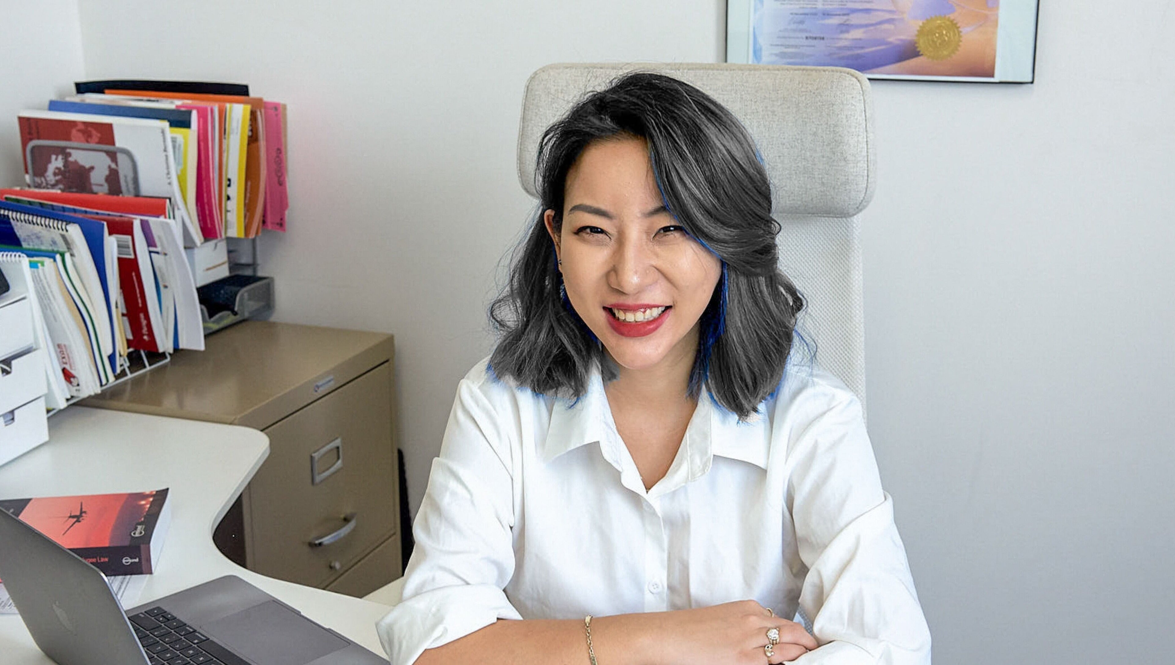 Professional consultant smiling at desk in Nohproblem Immigration and Education Consulting, Vancouver, BC.