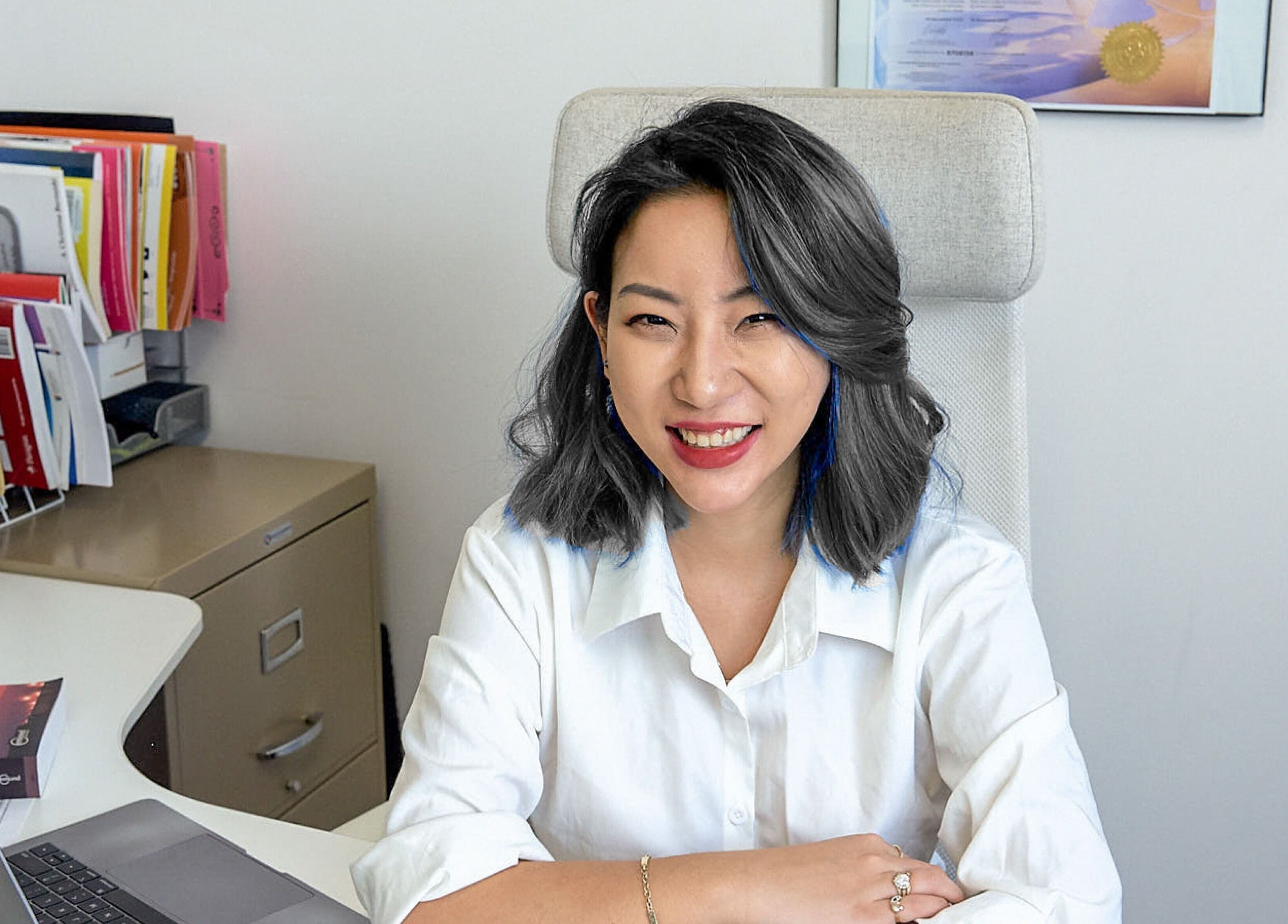 Professional consultant smiling at desk in Nohproblem Immigration and Education Consulting, Vancouver, BC.