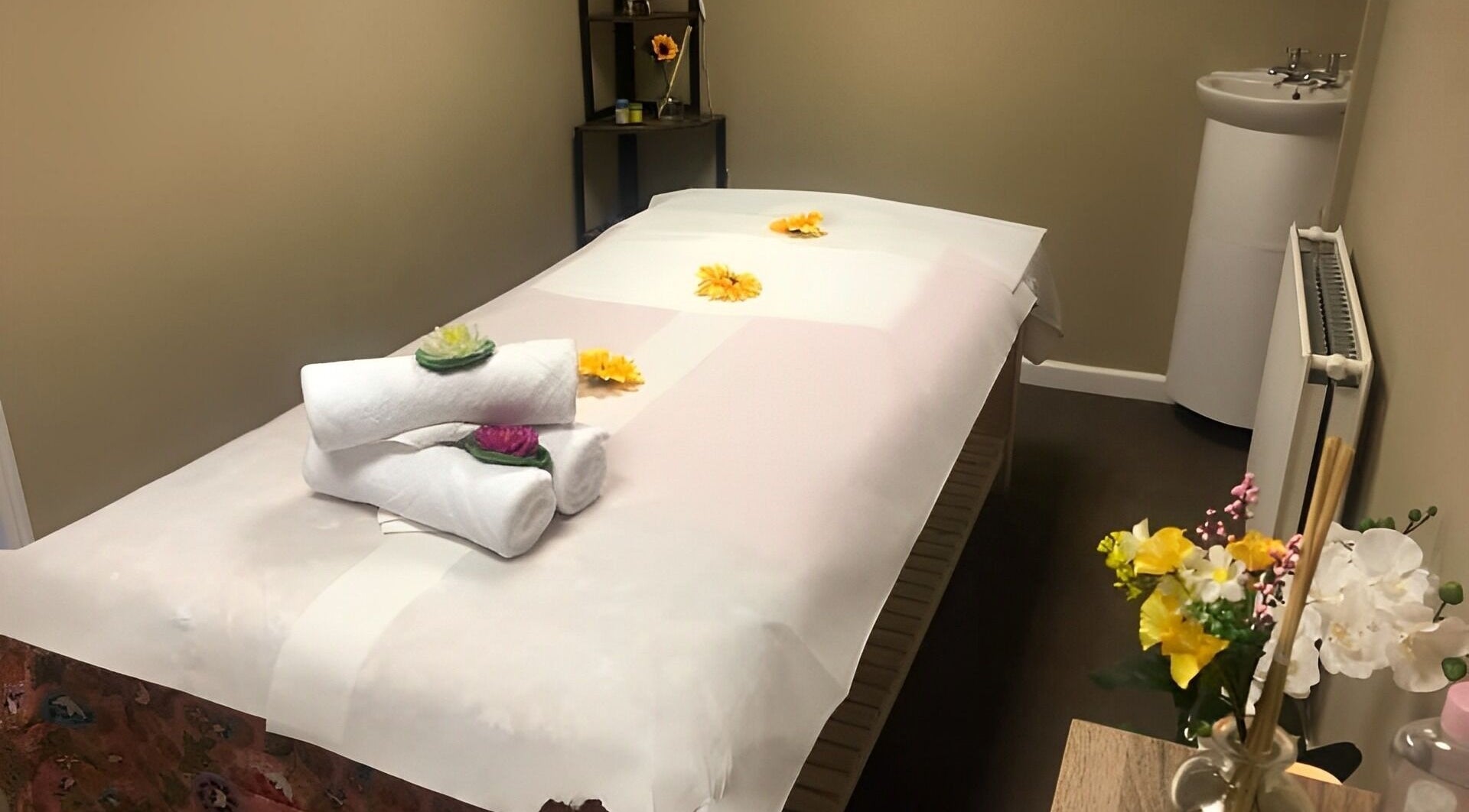 Relaxing massage room at Phaya Thai Therapy in Bristol, England, GB with flowers and plush towels.