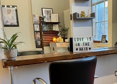 Stylish salon setup at The Hair Artist, Dublin. Elegant decor with a light-up sign and potted plant.