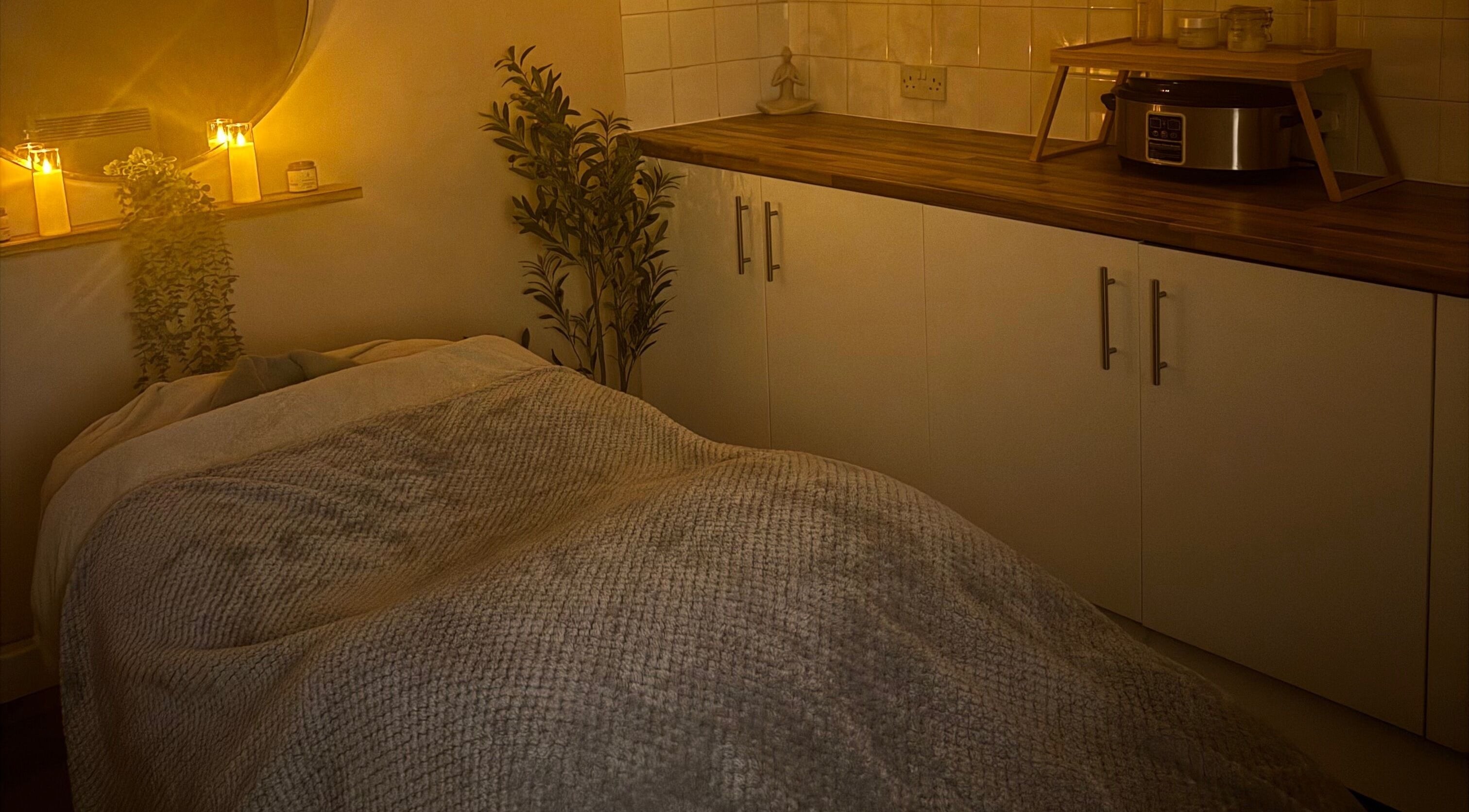 Cozy spa room at Simply Beauty Norwich, Norwich, England, GB with candles and a massage table.