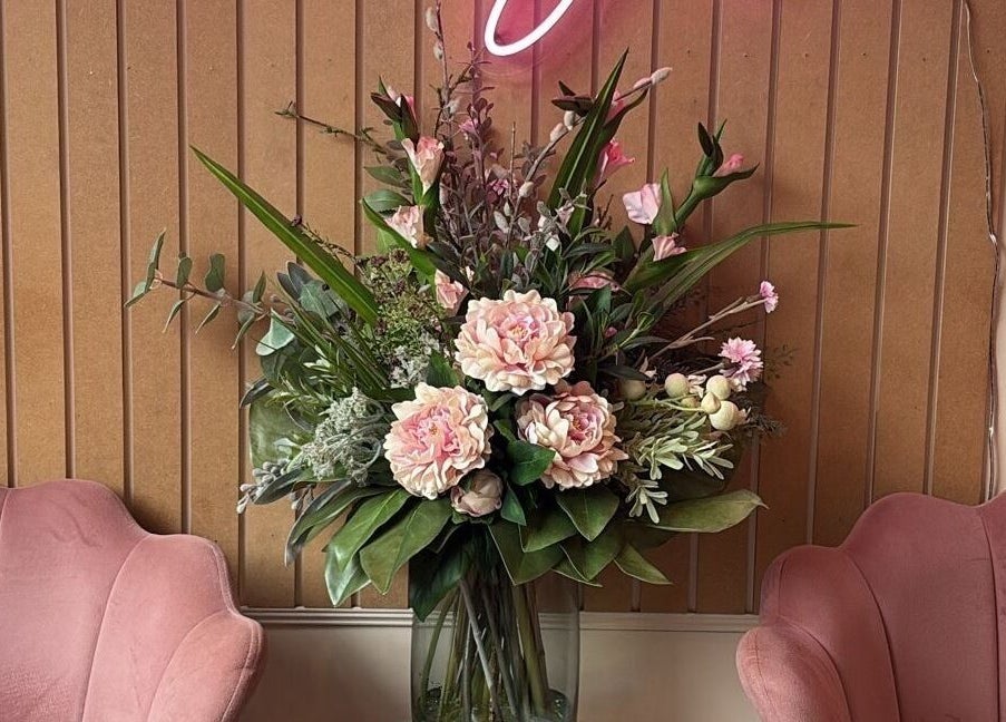 Luxurious floral arrangement at Simply Beauty Norwich, Norwich, England, GB, between plush pink chairs.