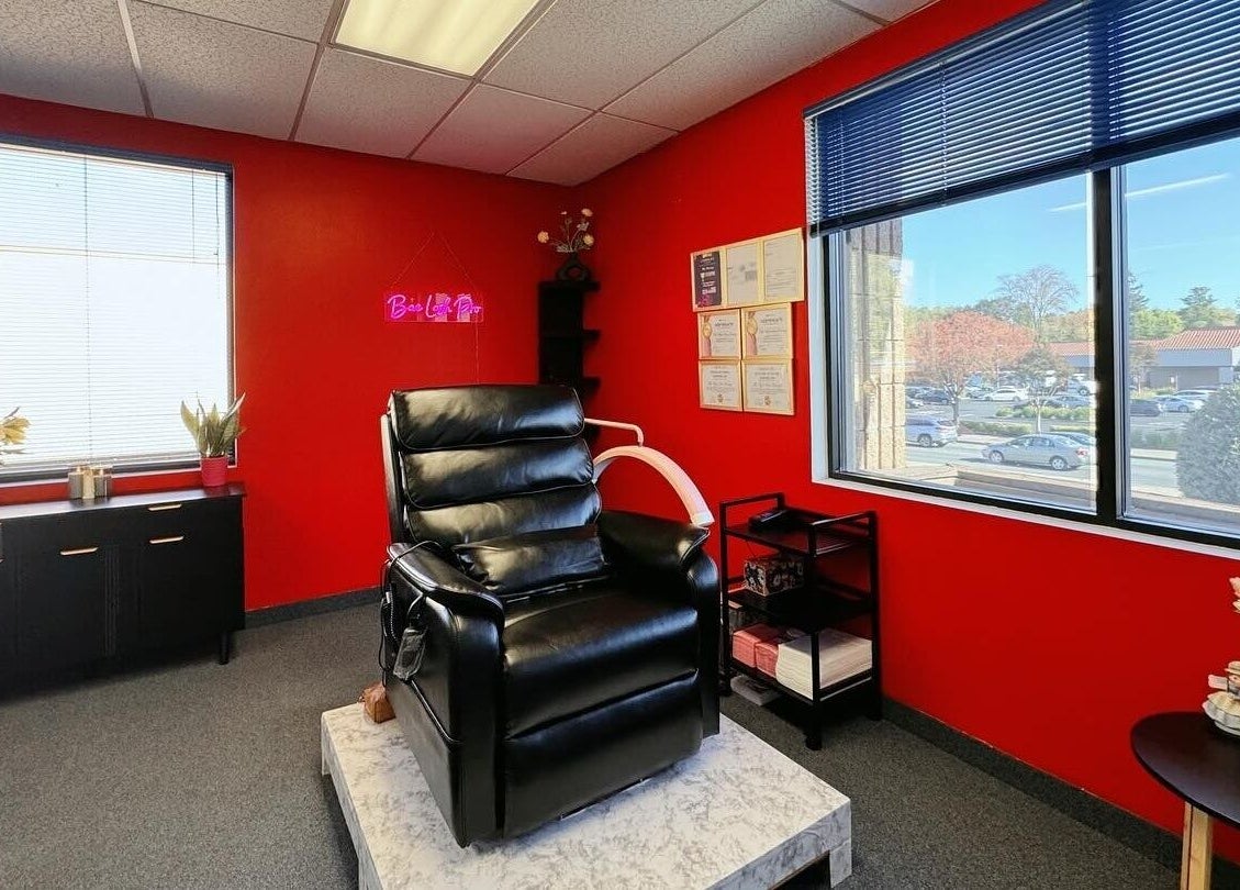 Modern lash room at Bae Lash Pro, San Jose, California, US, featuring a sleek black chair and vibrant red walls.