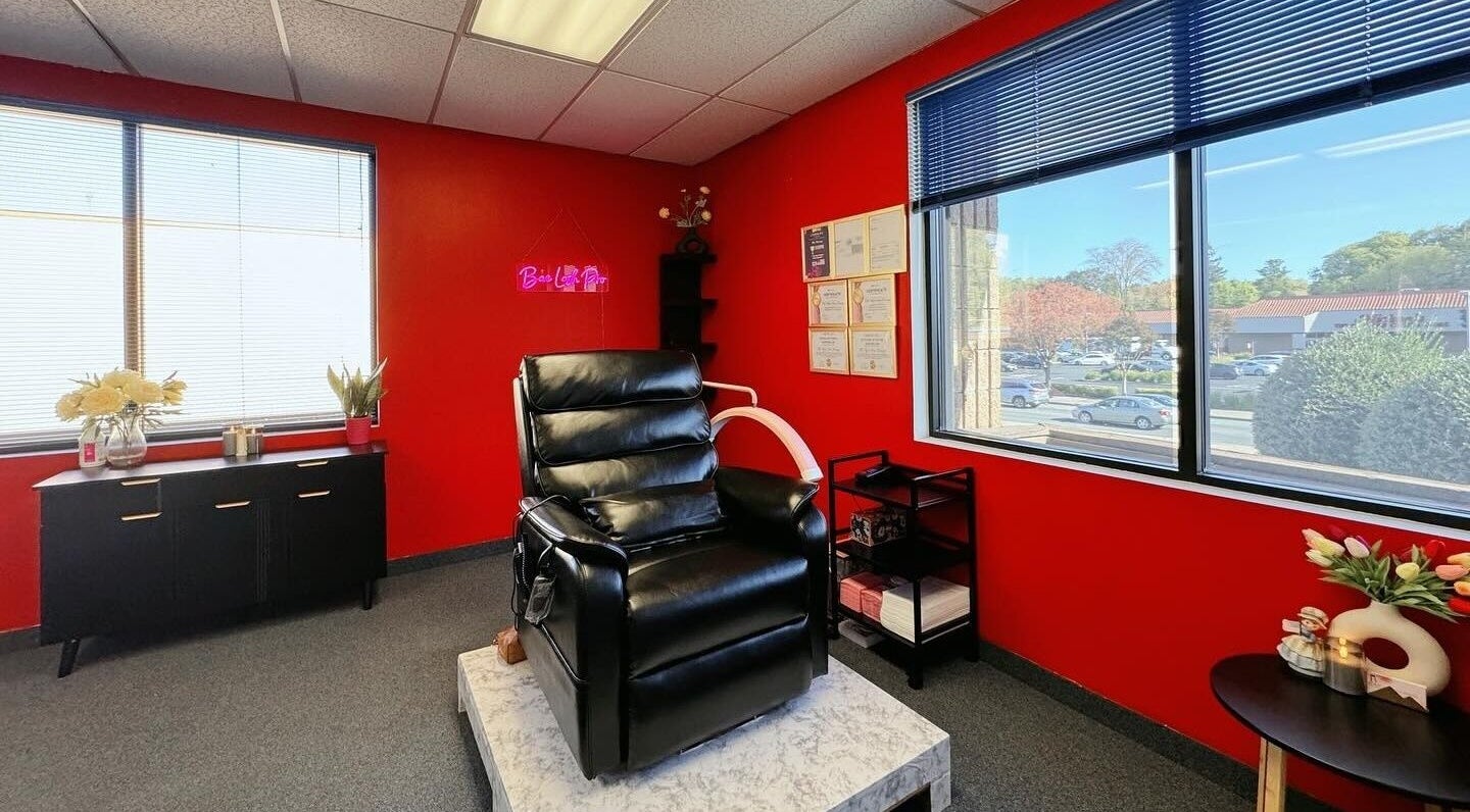 Modern lash room at Bae Lash Pro, San Jose, California, US, featuring a sleek black chair and vibrant red walls.