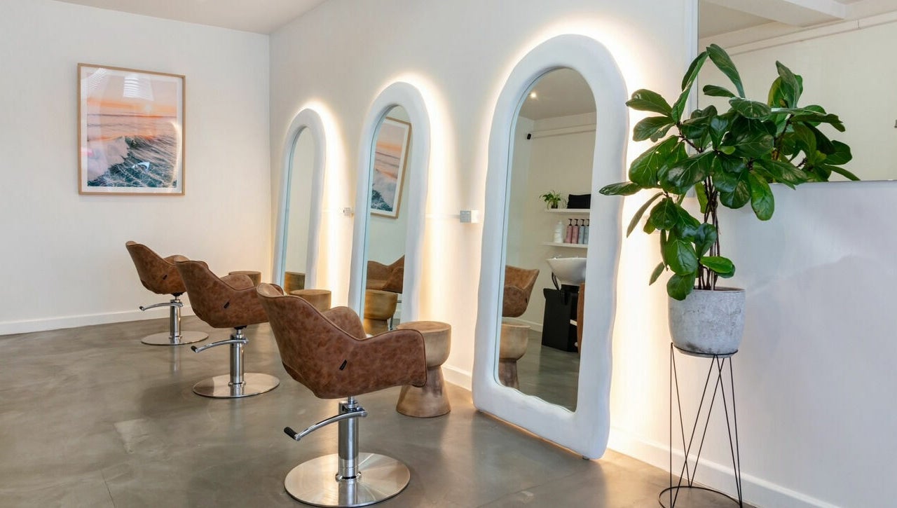 Sleek interior of That Girl Studio in St Kilda, Melbourne, featuring stylish chairs and mirrors.