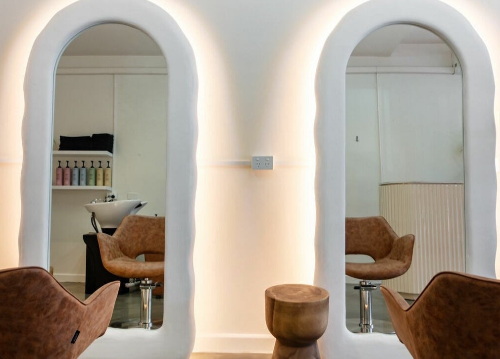 Chic salon at That Girl Studio in St Kilda, Melbourne, with stylish chairs and illuminated mirrors.