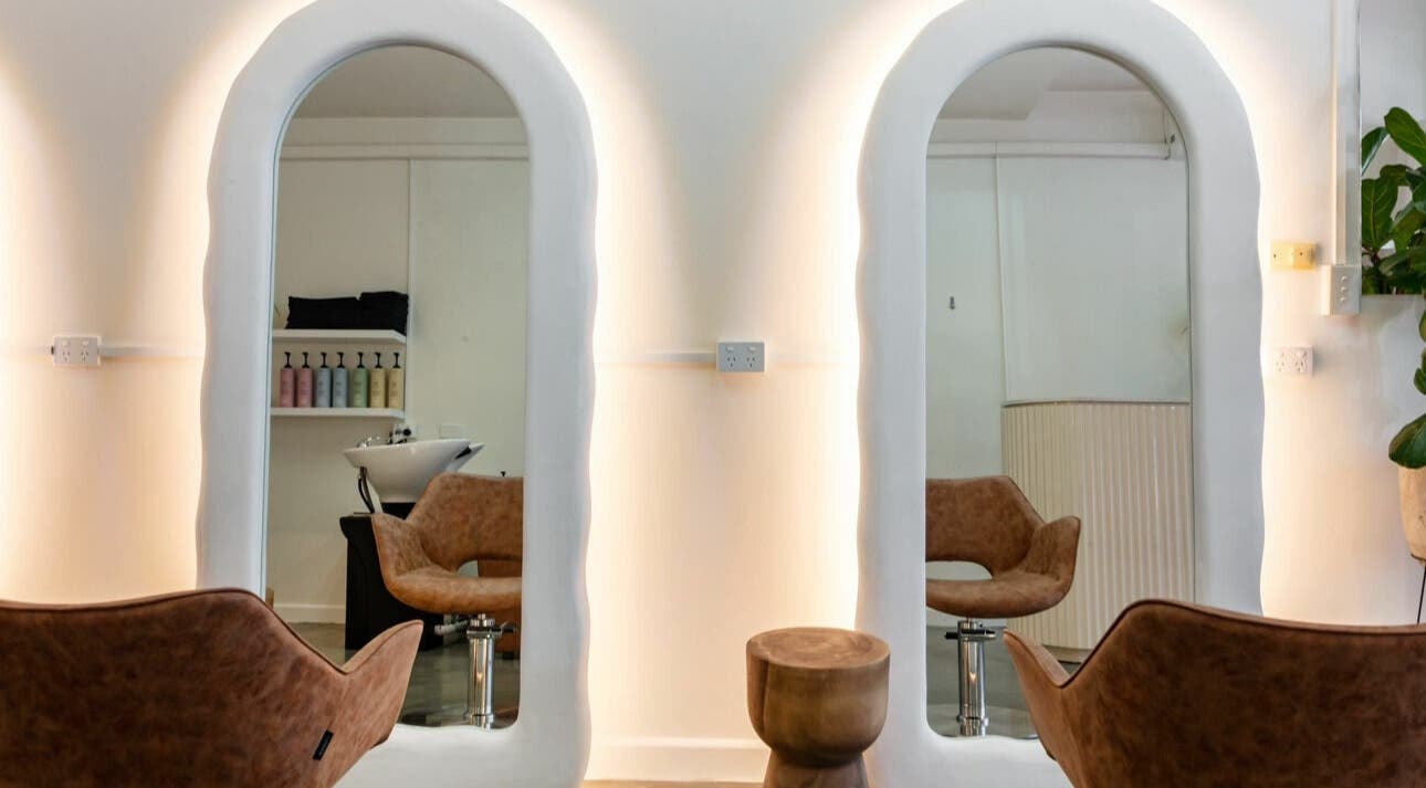 Chic salon at That Girl Studio in St Kilda, Melbourne, with stylish chairs and illuminated mirrors.