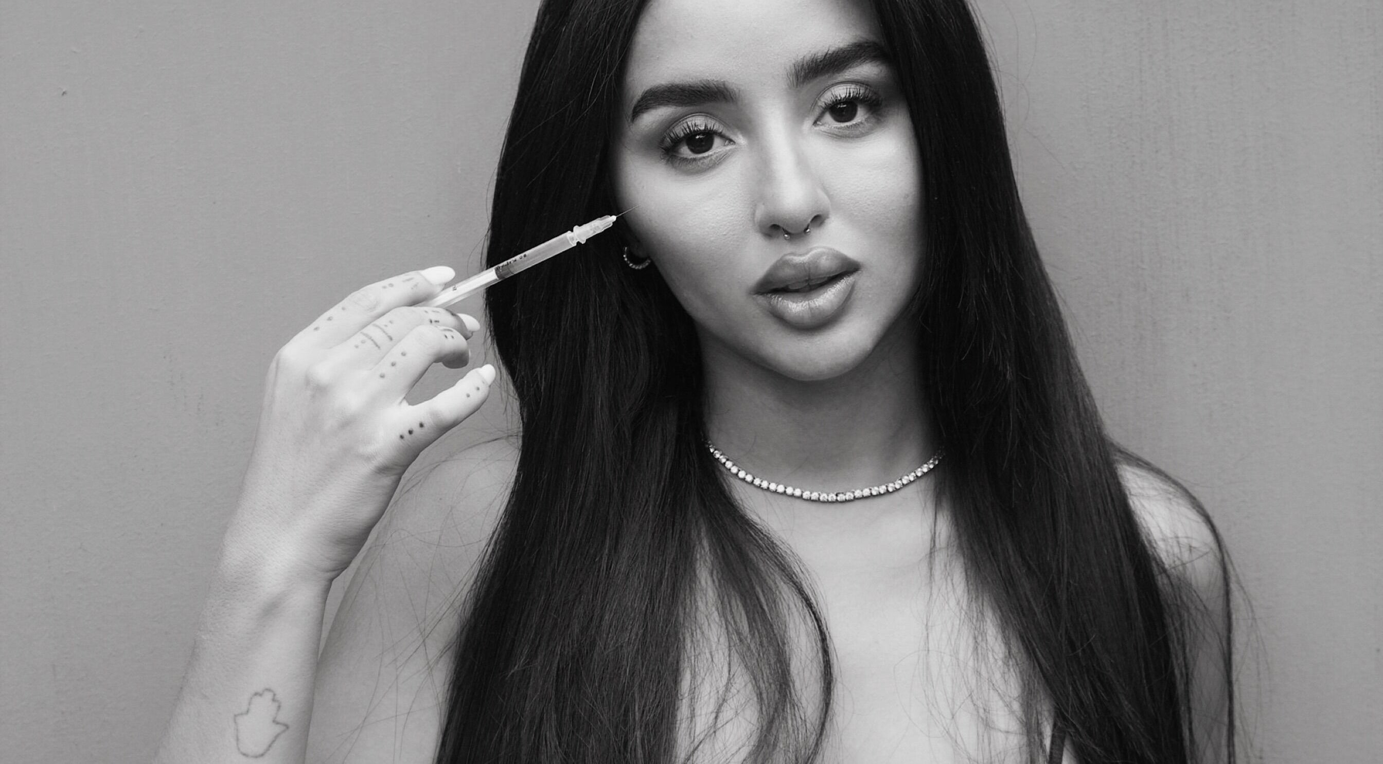 Model holding syringe at Aesthetic Atelier, Horsham, England, GB, reflects beauty and wellness expertise.