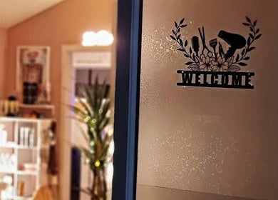 Entrance door with a welcome decal at Hue of Aura, Timaru, Canterbury, NZ, depicting a cozy salon interior.