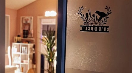 Entrance door with a welcome decal at Hue of Aura, Timaru, Canterbury, NZ, depicting a cozy salon interior.