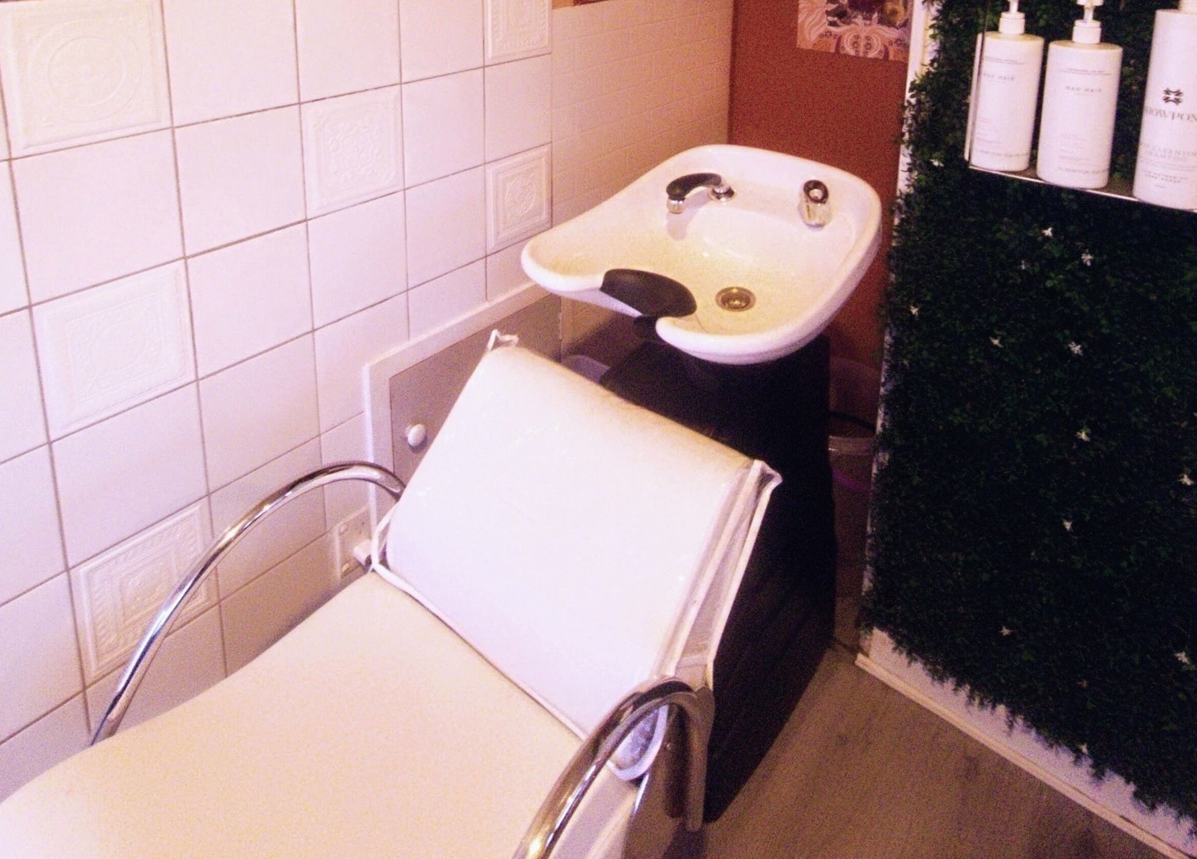 Relaxing hair wash station at Hue of Aura, Timaru, Canterbury, NZ, with elegant white chair and basin.