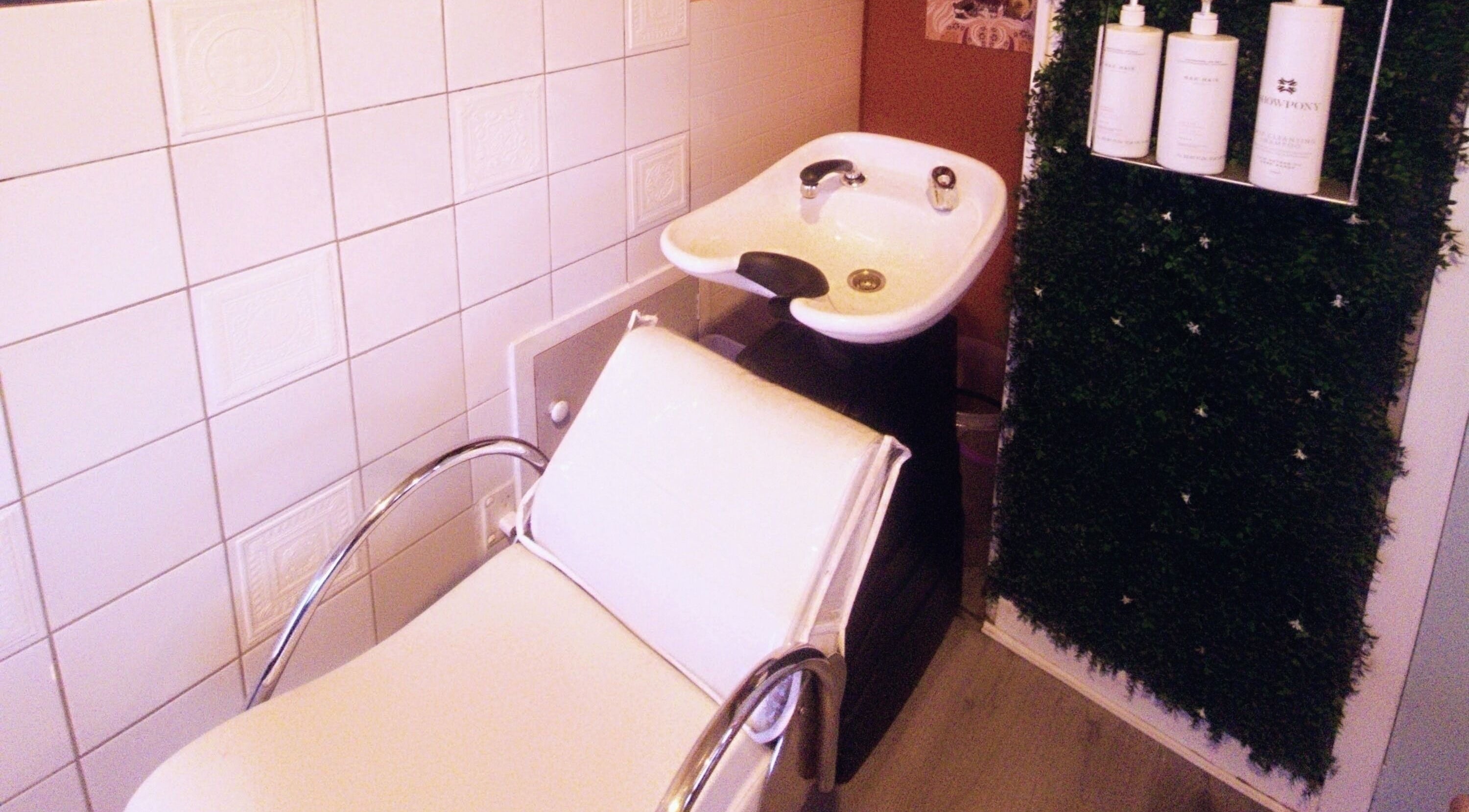 Relaxing hair wash station at Hue of Aura, Timaru, Canterbury, NZ, with elegant white chair and basin.