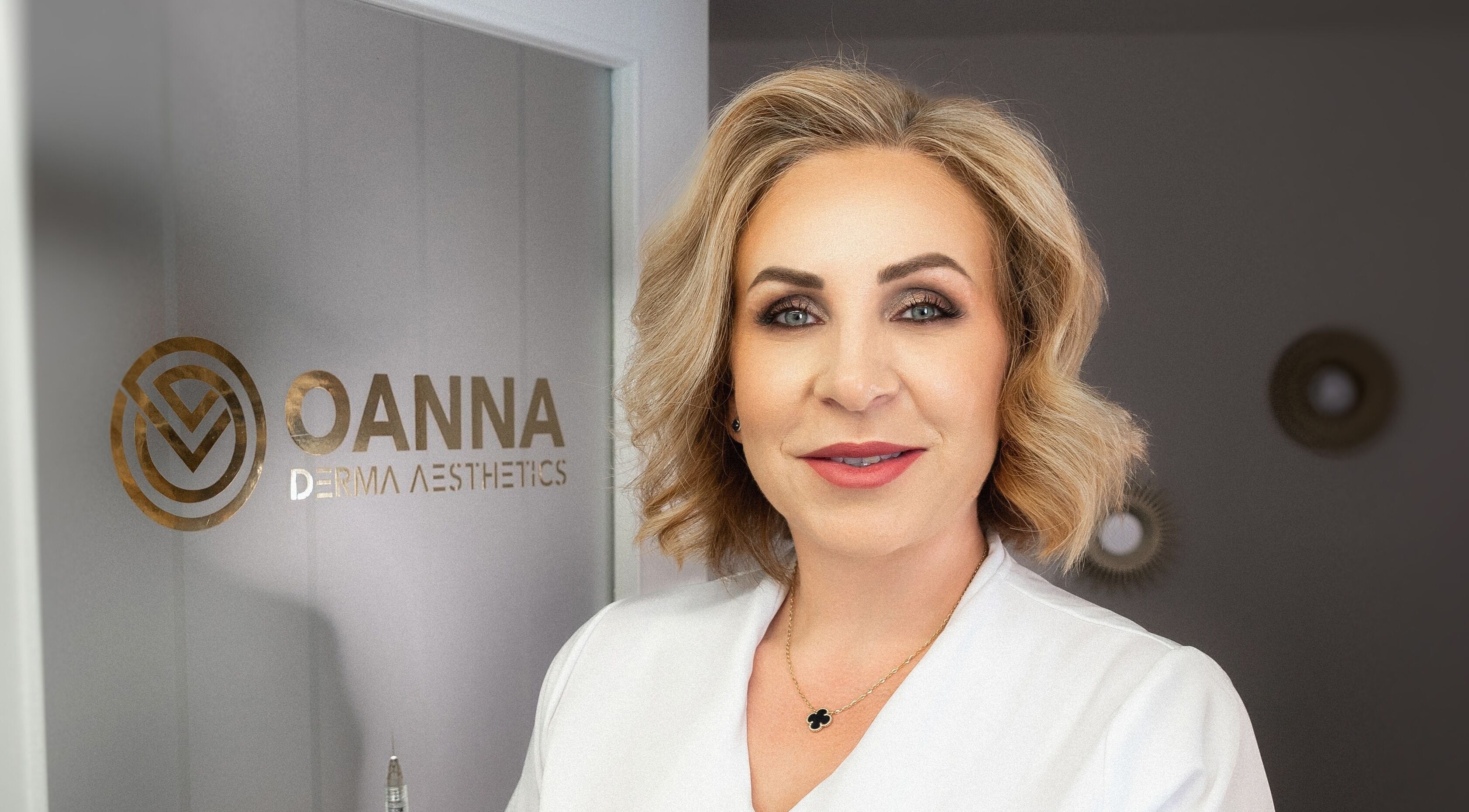 Professional at Oanna Aesthetics in Corby, England, GB standing by the logo displaying expert skincare services.