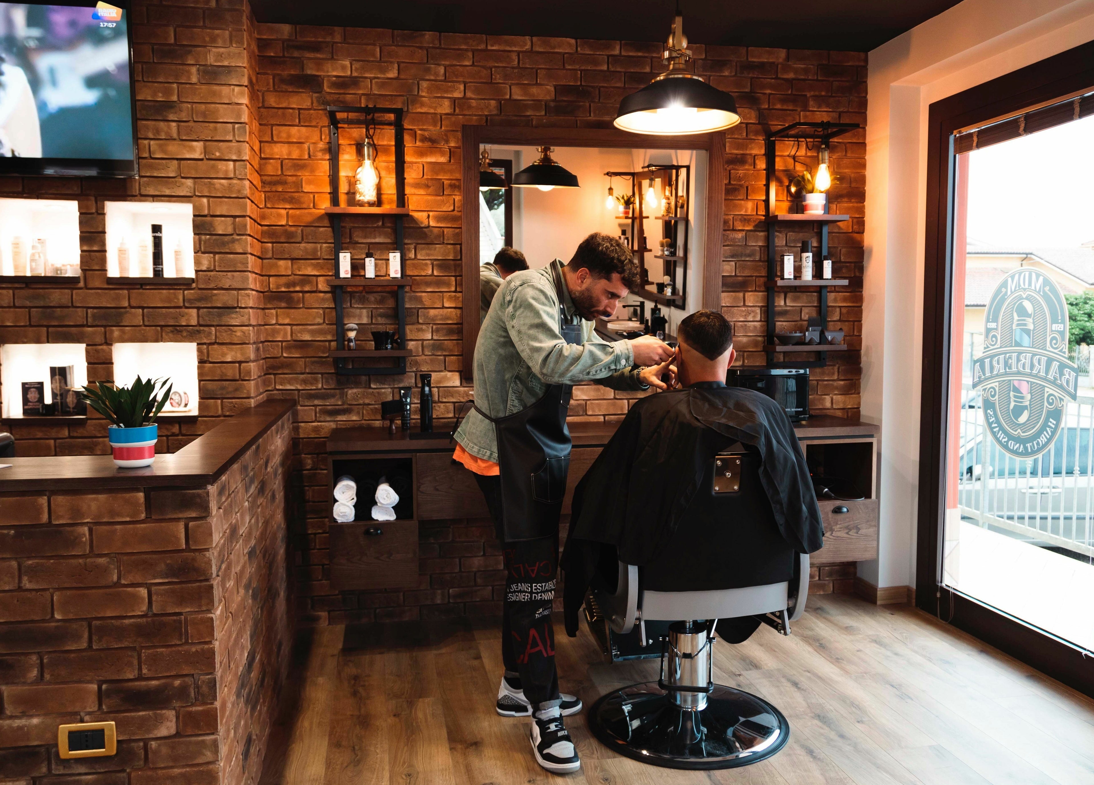 Interno di MDM Barberia ad Abruzzo, Abruzzo, IT con cliente in poltrona e barber al lavoro.