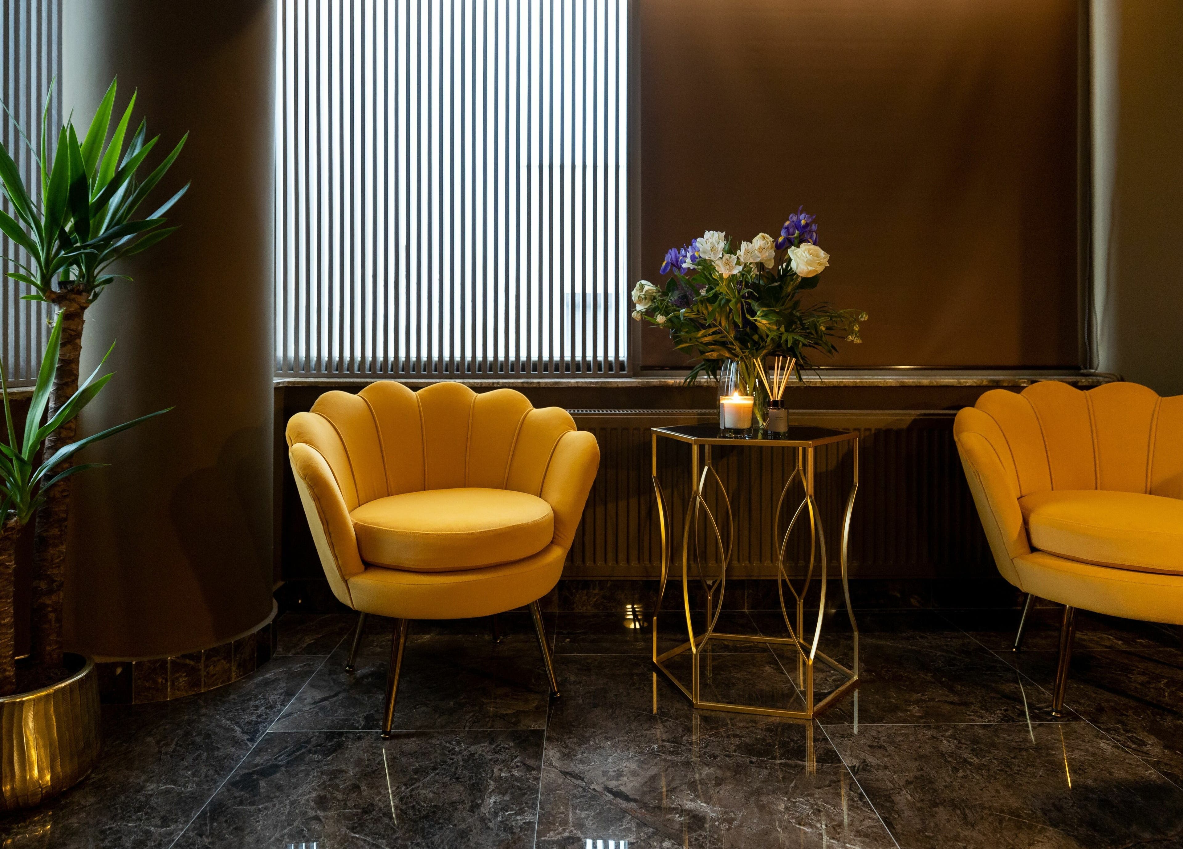 Colț relaxant la Baliss Spa, București, cu fotolii galbene și masă elegantă decorată cu flori.