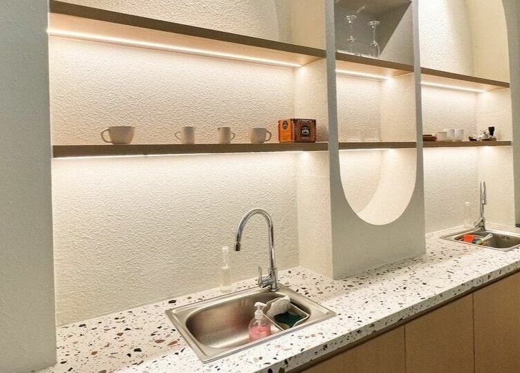 Modern sink area at Gemini Japanese Hair Salon, Hồ Chí Minh, VN with terrazzo countertop and shelves.