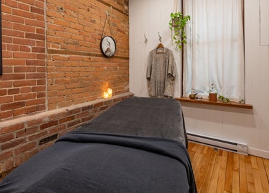 Salle de soins sereine à La Loge Soins & Esthétique, Montréal, Québec, CA, avec briques apparentes et bougies.