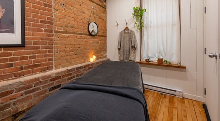 Salle de soins sereine à La Loge Soins & Esthétique, Montréal, Québec, CA, avec briques apparentes et bougies.