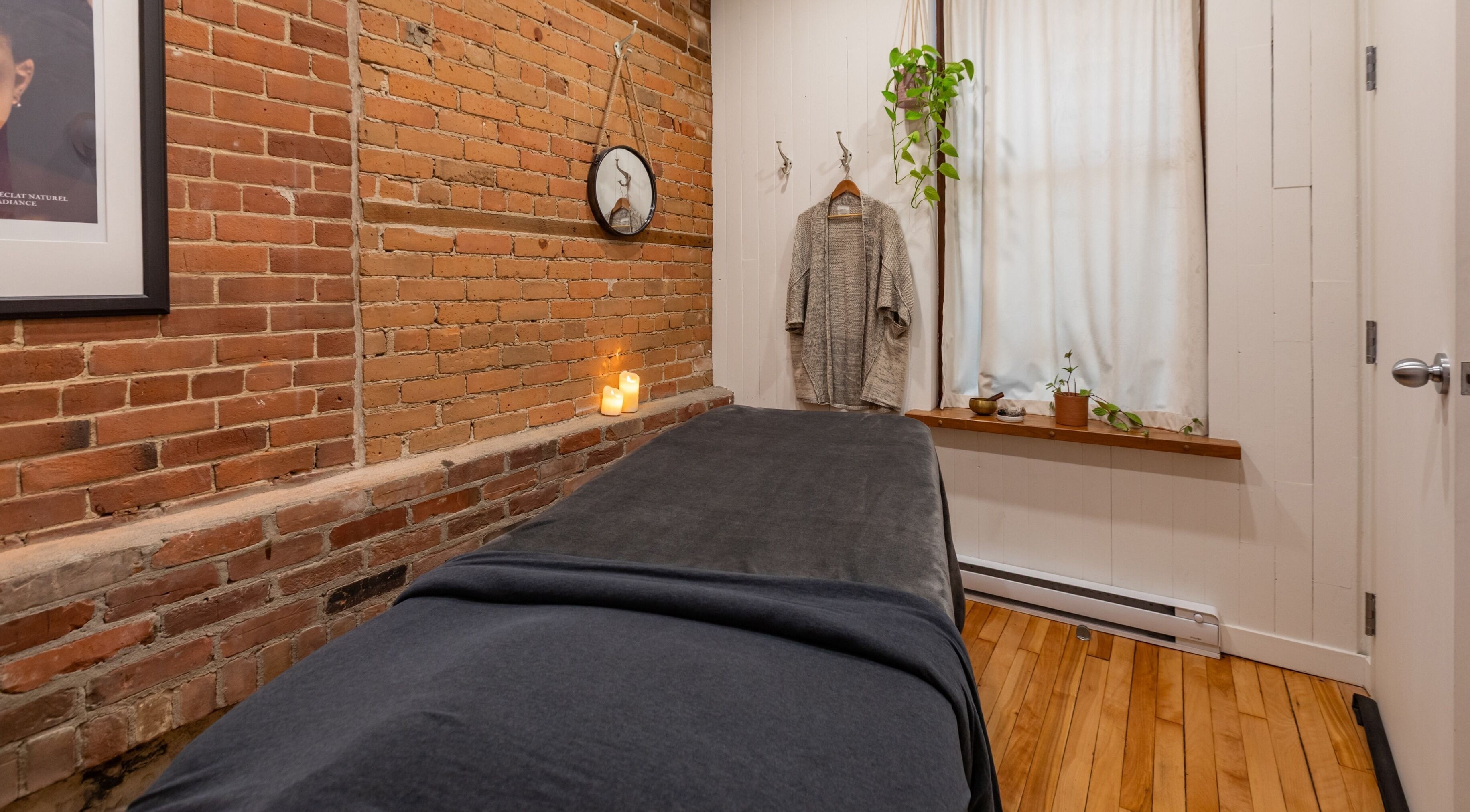 Salle de soins sereine à La Loge Soins & Esthétique, Montréal, Québec, CA, avec briques apparentes et bougies.