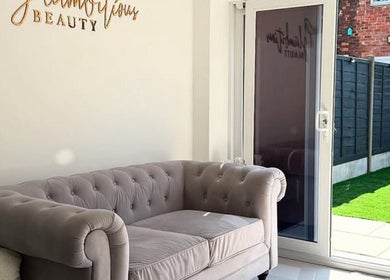 Elegant lounge at Glambitious Beauty in Hull, England, GB showcasing a plush grey sofa by a bright window.