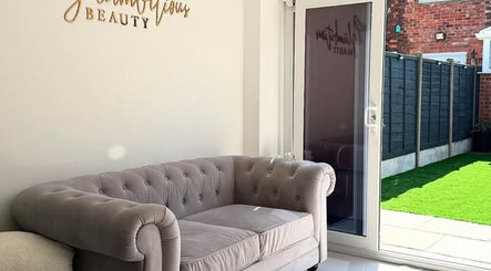 Elegant lounge at Glambitious Beauty in Hull, England, GB showcasing a plush grey sofa by a bright window.