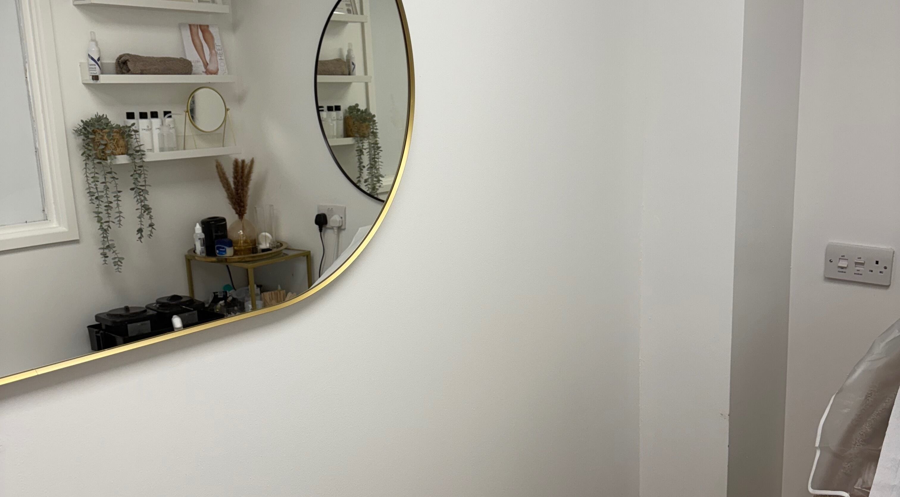 Elegant beauty room with a round mirror at Fiona Watton Beauty, Bude, England, GB.