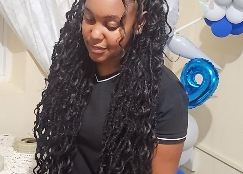 Smiling woman with locs at Zaphina Locs, Bridgetown, Saint Peter, BB, next to festive balloons.