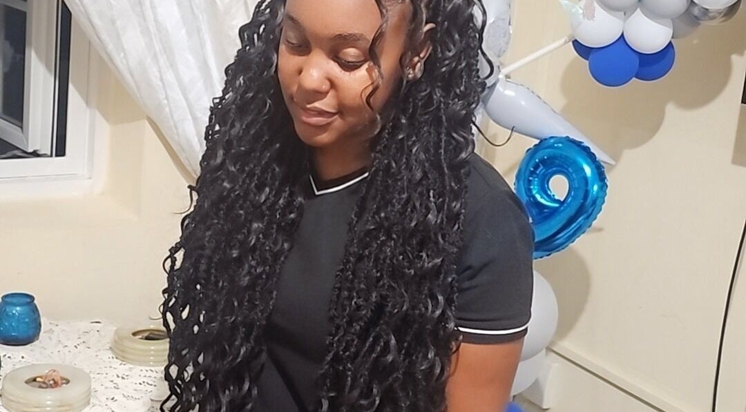 Smiling woman with locs at Zaphina Locs, Bridgetown, Saint Peter, BB, next to festive balloons.
