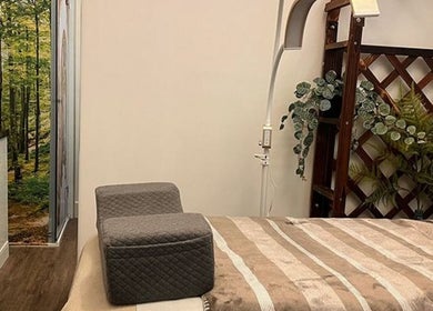Relaxing treatment room at PUREGLAM BEAUTY in Melbourne, Victoria, AU, featuring a serene forest mural and cozy setup.